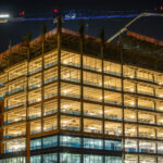 Modern residential home under construction in 2026 with construction workers, building materials, and real estate investment planning.